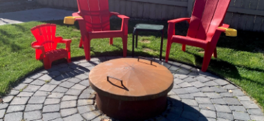 Firepit in a back yard with two red chairs
