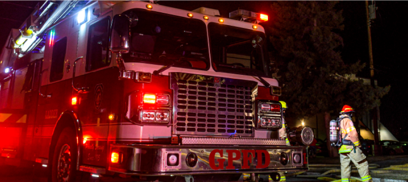 Firefighter standing in front of a fire truck at an emergency scene